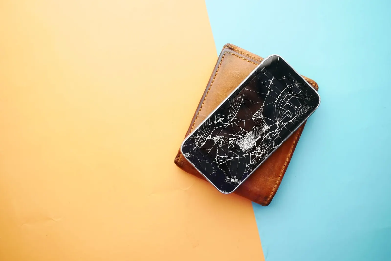 Phone with a broken screen resting on a wallet