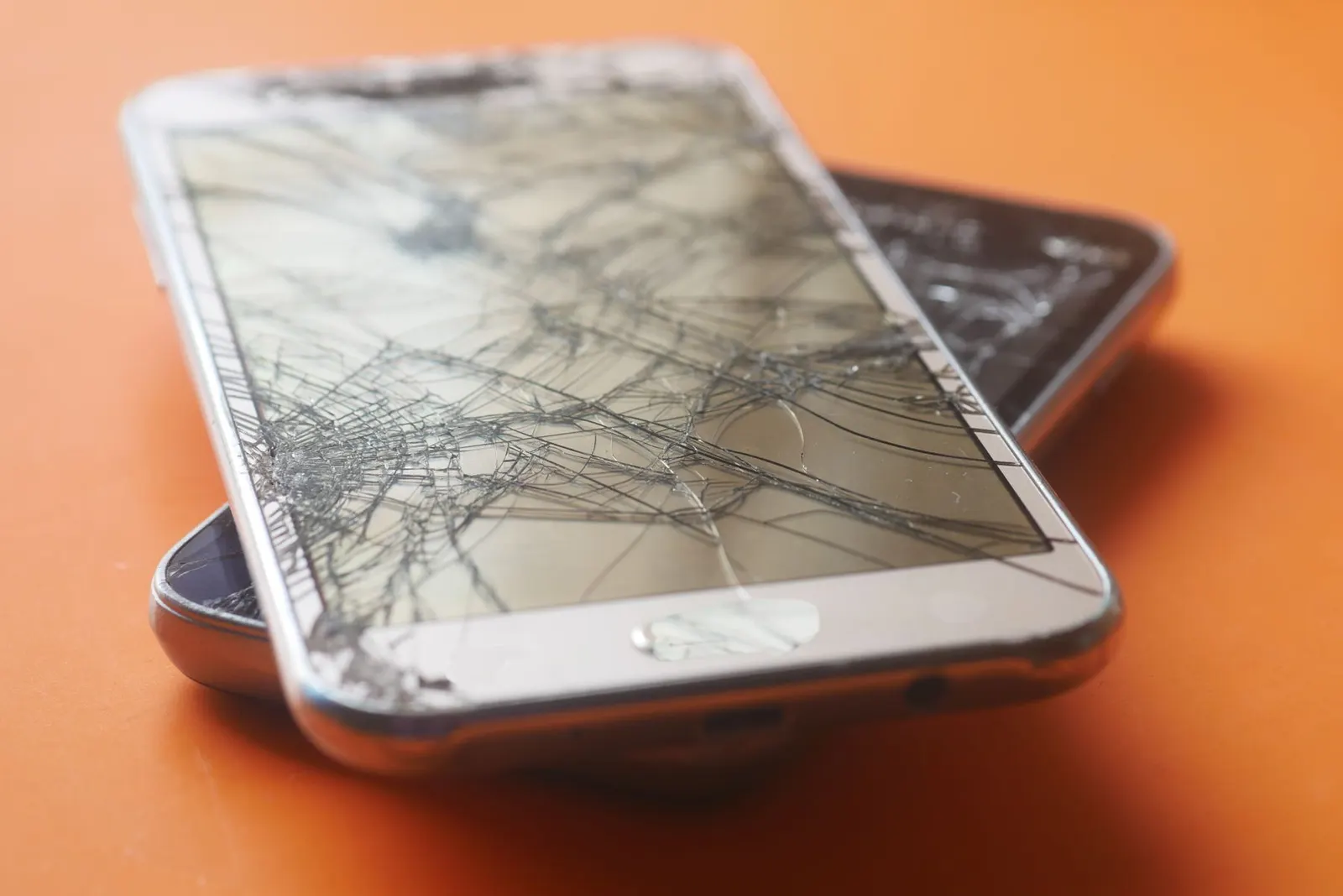 Smartphones with cracked screens on a repair table