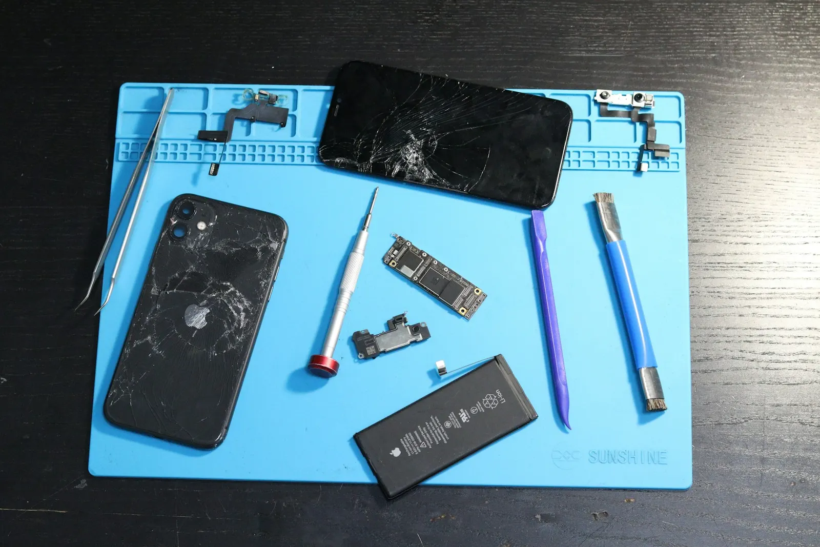 Disassembled phone parts on a repair mat
